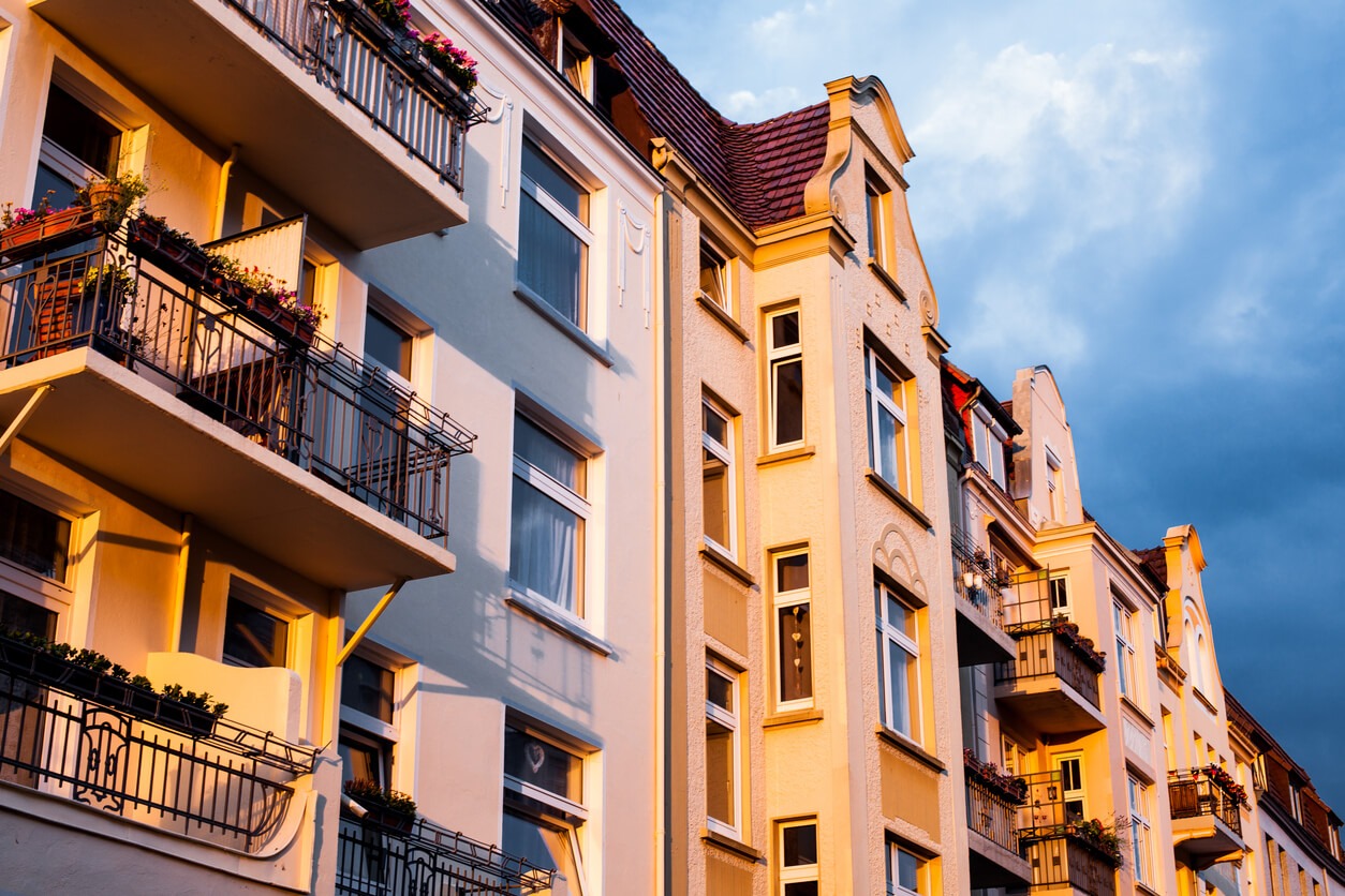 Die Sonne scheint auf Altbauwohnungen. Über dem Gebäude ein bewölkter Himmel.
